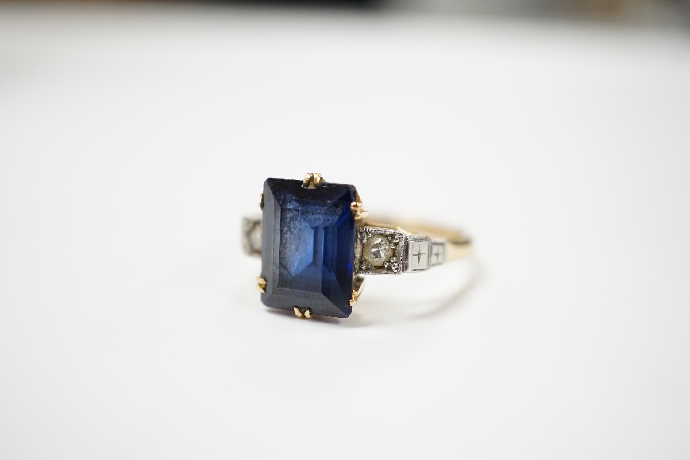 An 18ct, plat and single stone emerald cut synthetic? sapphire set dress ring with diamond set shoulders, size P/Q, gross weight 4.7 grams.